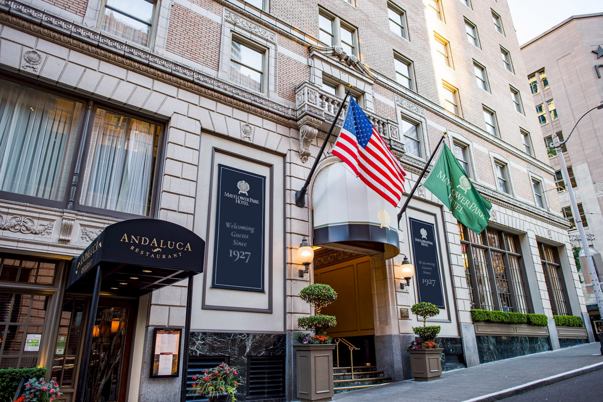 A stone building with a black awning and flags flying outside the entrance.