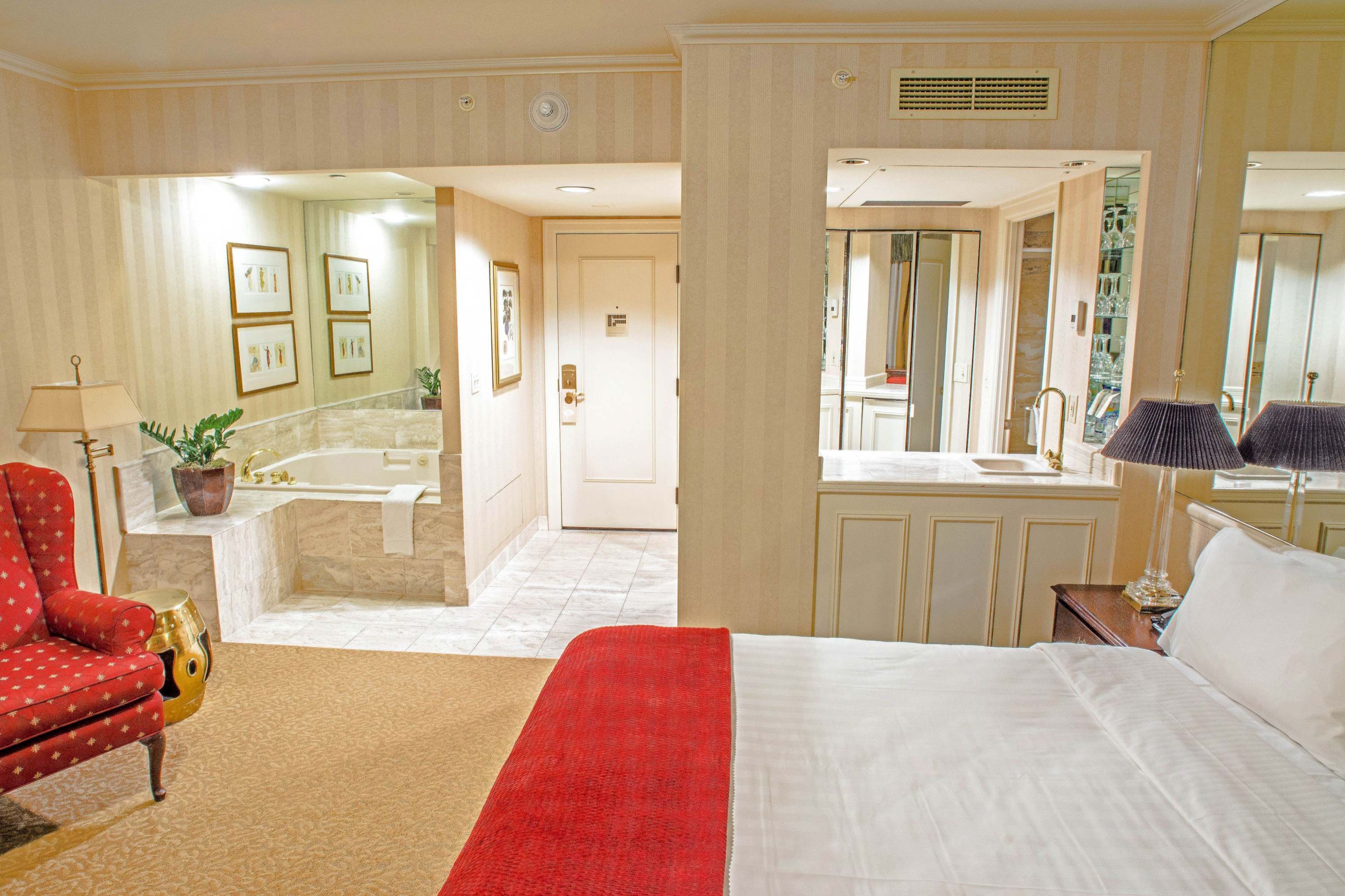 A wide view of a hotel room with a bed, chair, and bathroom in the background.
